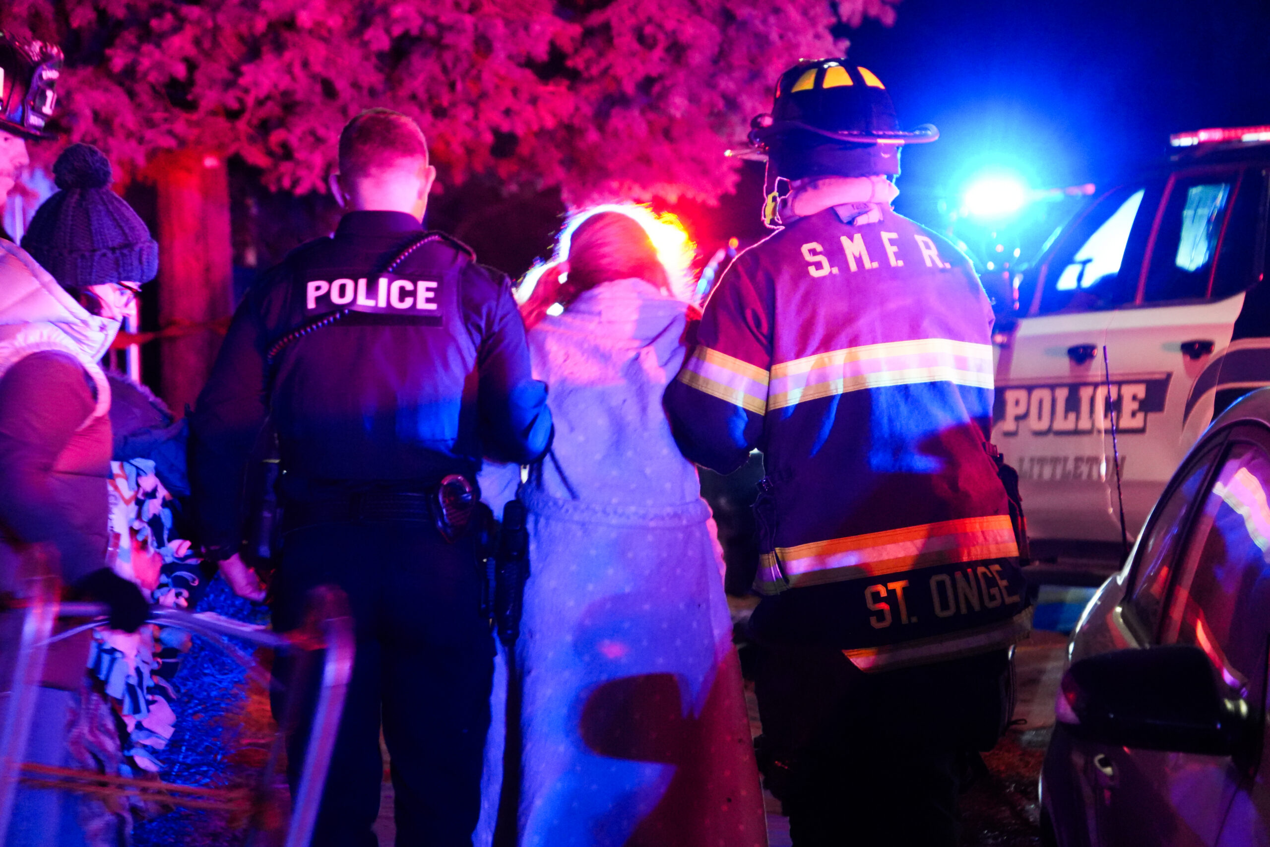Police captain and fire fighter helping a woman
