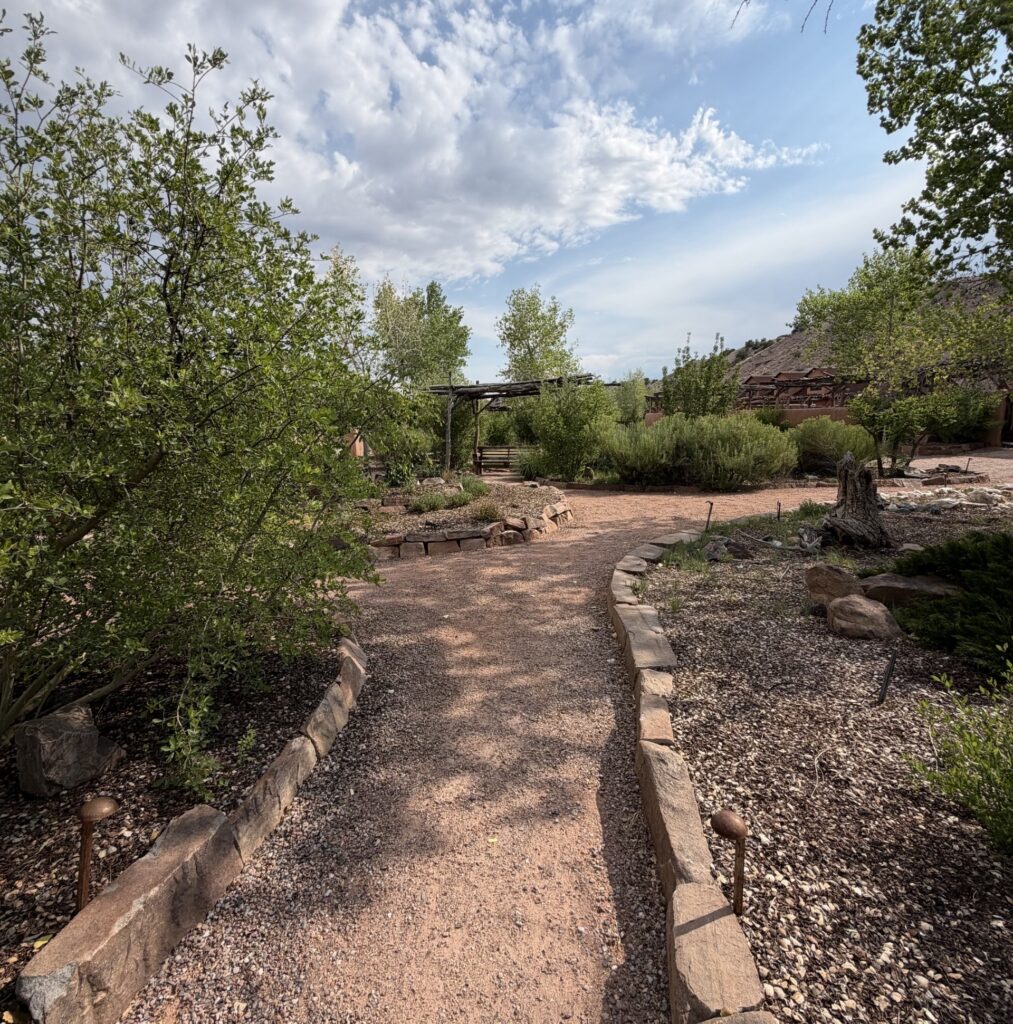 Stone-lined gravel garden path winding toward a wooden pergola, symbolizing the leadership delegation journey from manager to multiplier