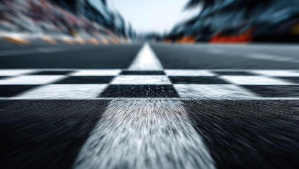 Blurred motion shot of a checkered finish line on a race track, suggesting a line in motion
