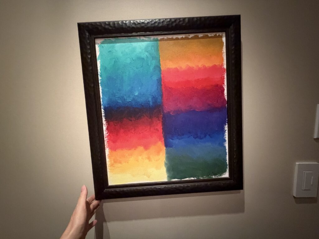 A hand steadying a picture frame slightly off-center